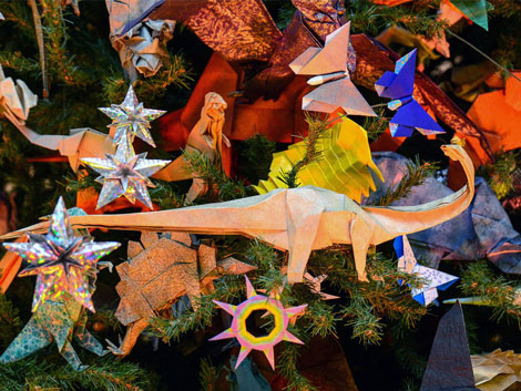 Close up image of origami on the tree including starts, dinosaurs, and butterflies. 