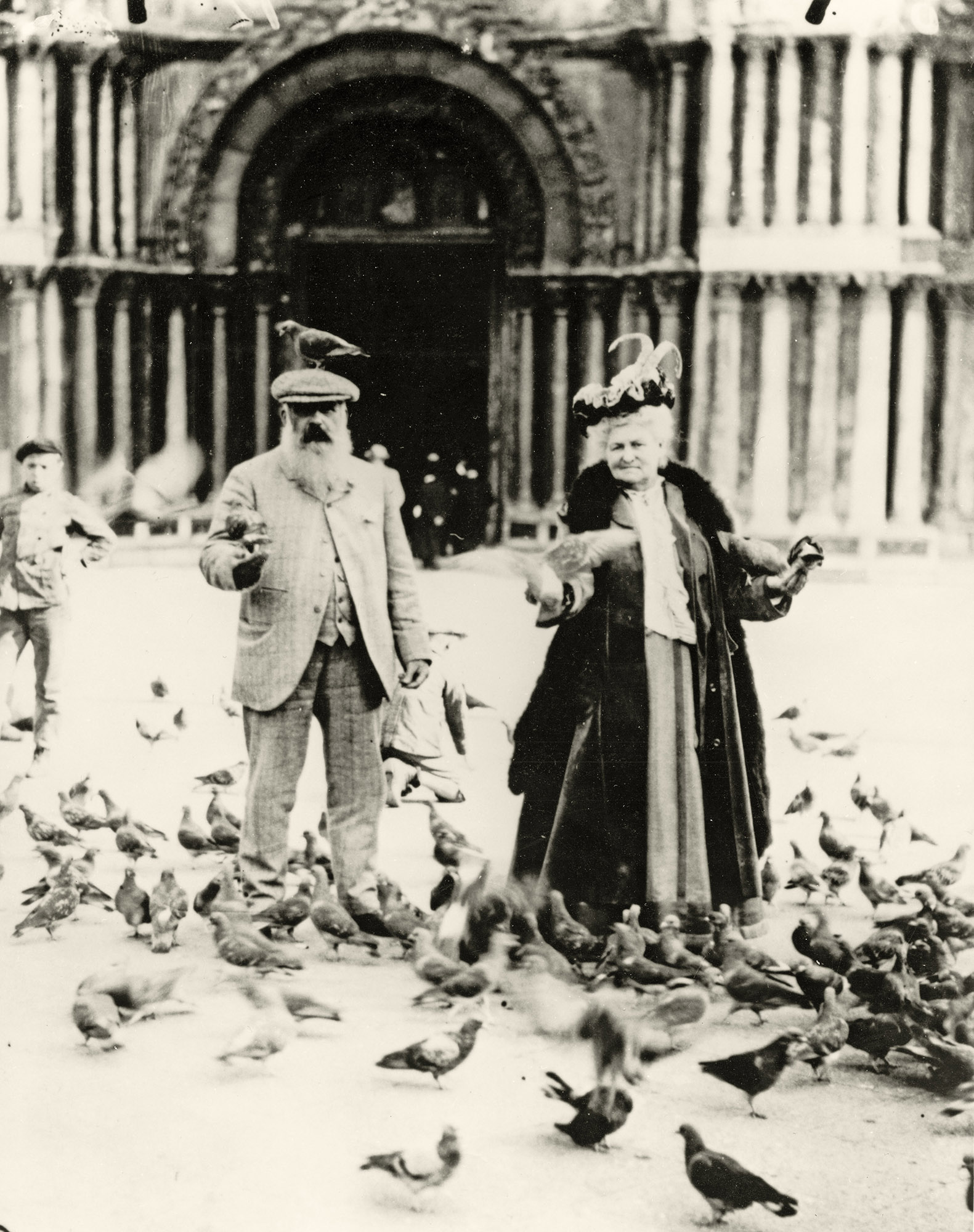 An elderly couple covered in pigeons