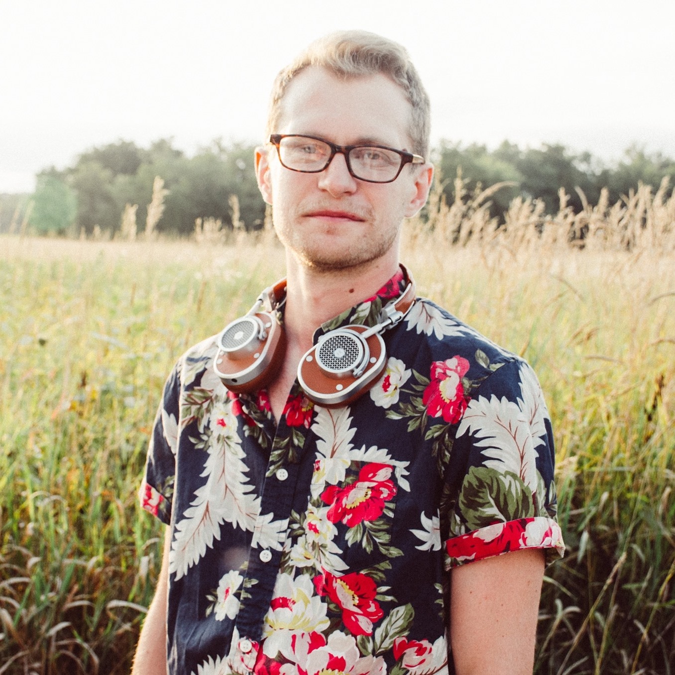 ID: Julian Loida stands outside in front of a field of grass.