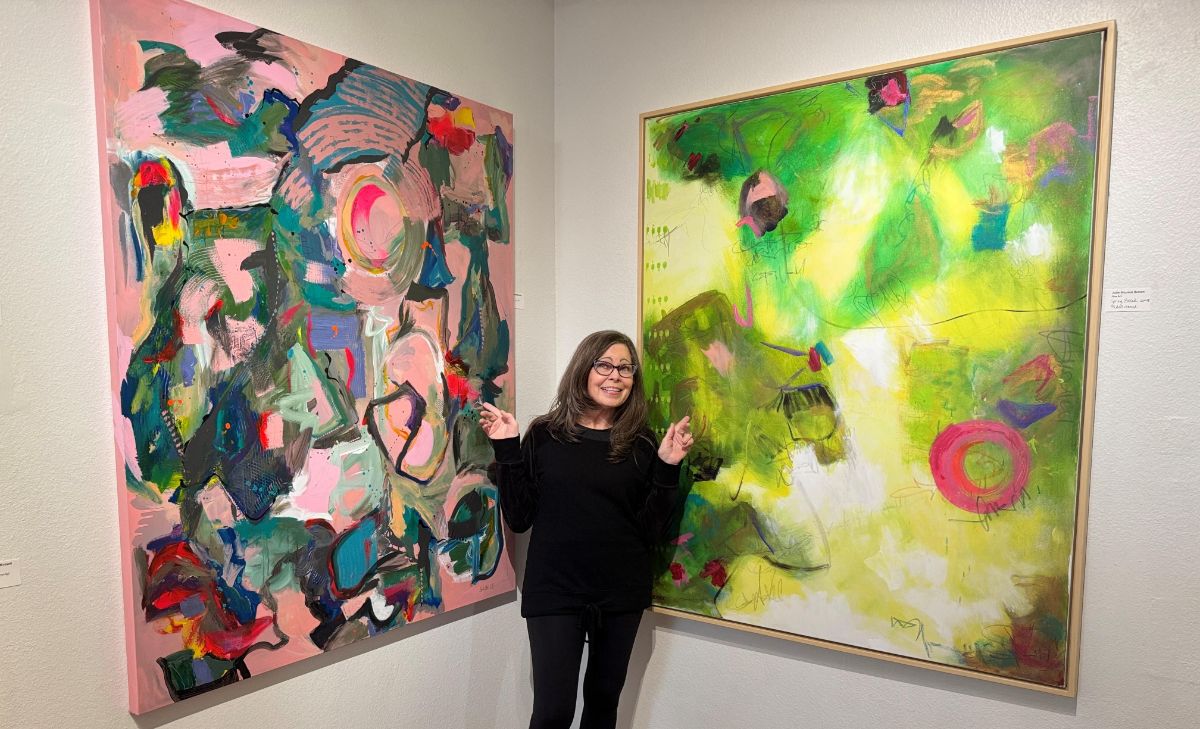 Artist Julie Shunick Brown in front of 2 paintings