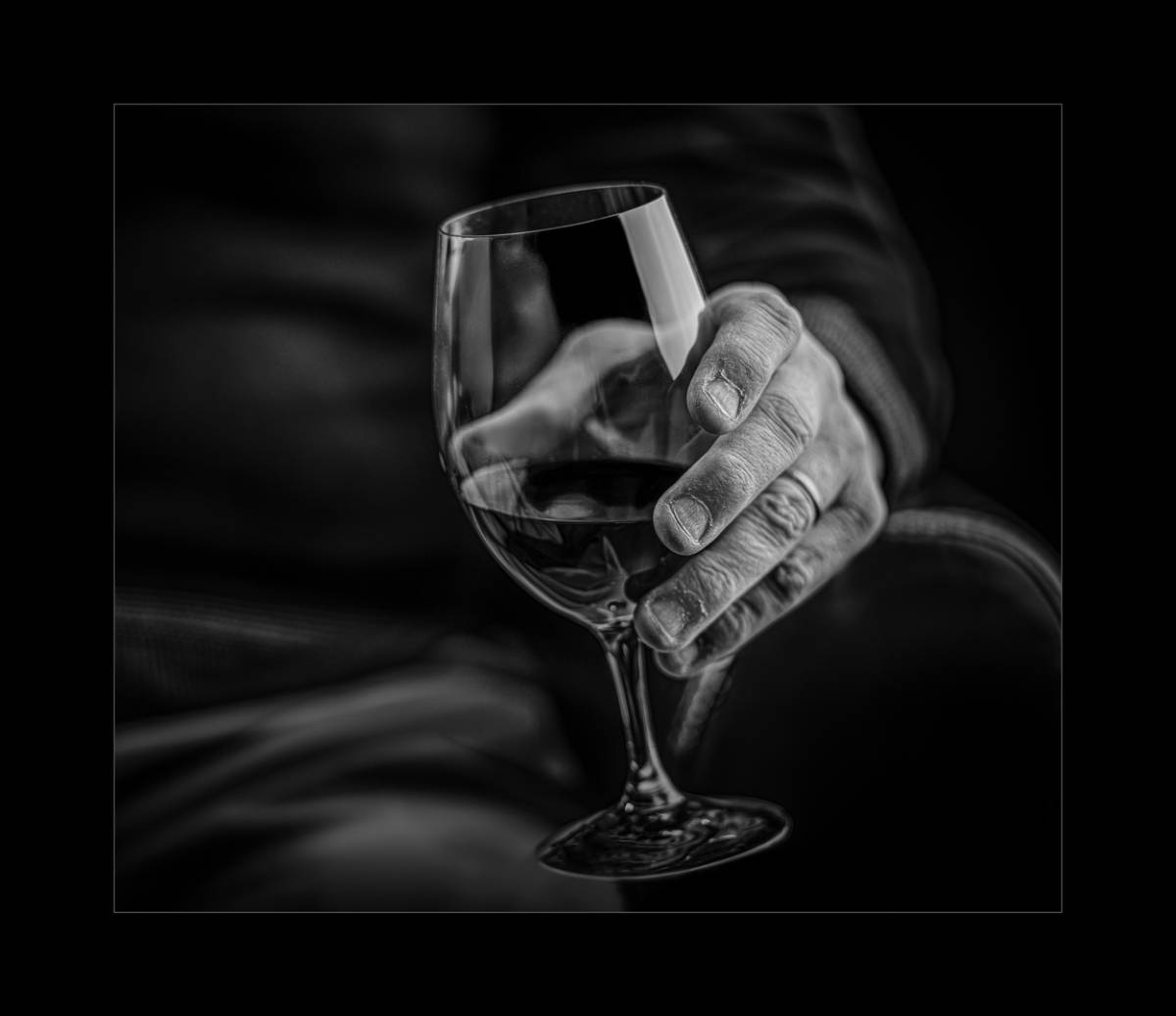 Black and white photograph of a hand holding a glass of wine