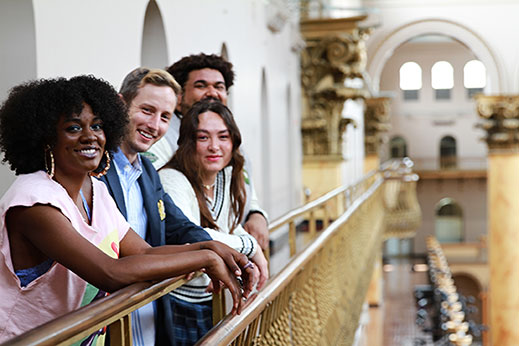 four young people leaning on a banister in the National Building Museum