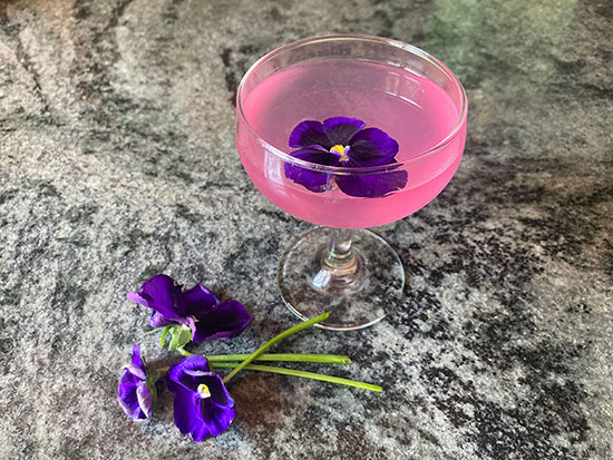 pansies with a glass of pink-colored liquid