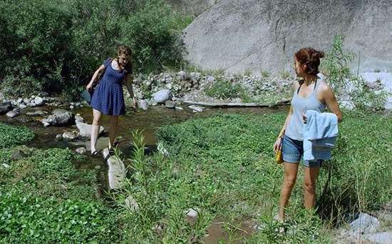 a film still showing two women crossing a stream