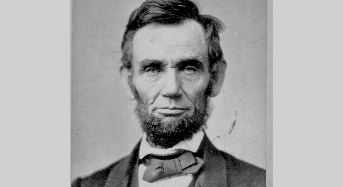 Abraham Lincoln, wearing his signature beard and a bow tie, looks directly into the camera. He is photographed from the chest up. Link to learn more.