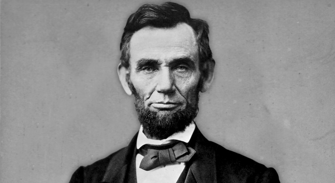 Abraham Lincoln, wearing his signature beard and a bow tie, looks directly into the camera. He is photographed from the chest up. Link to learn more.