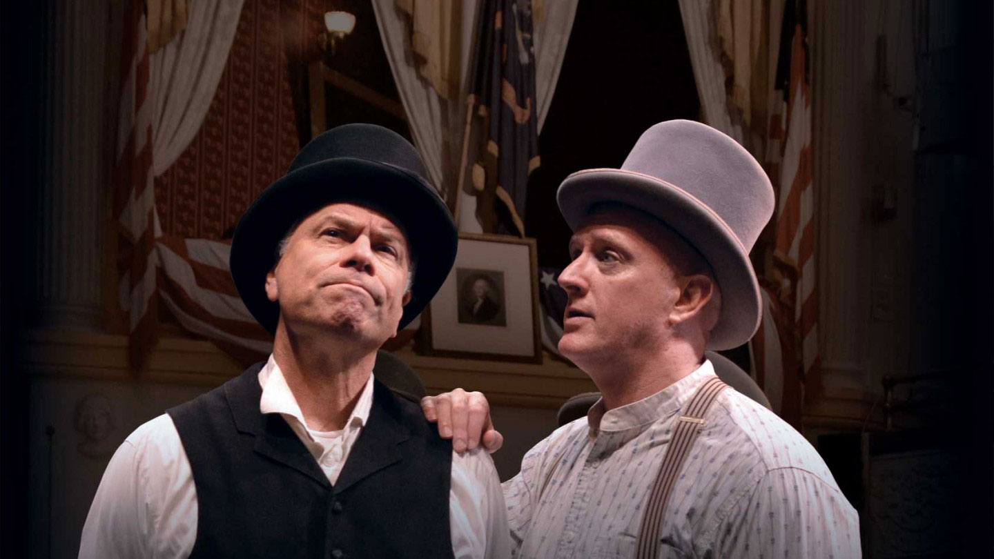 Two men in 1860s clothing comfort each other in front of the President's Box. Link to get tickets.