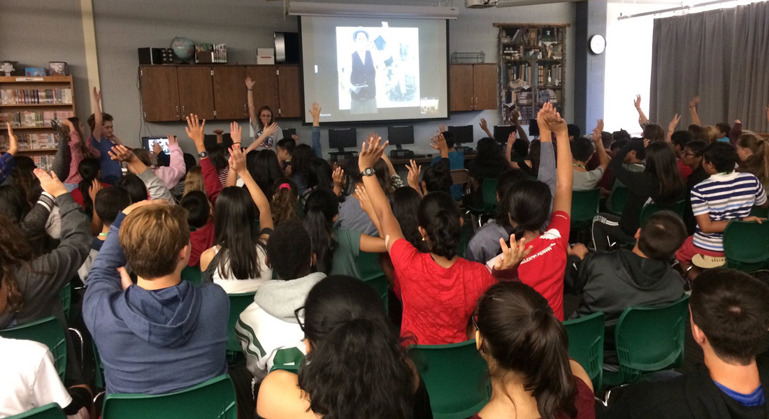 8th-graders in East Brunswick, NJ raise their hands to participate in videoconferencing session with Detective McDevitt.