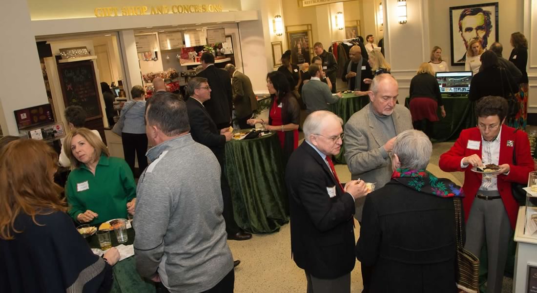 Ten adults stand at a reception in the Fords Theatre lobby, enjoy snacks and conversation. Link to join today.