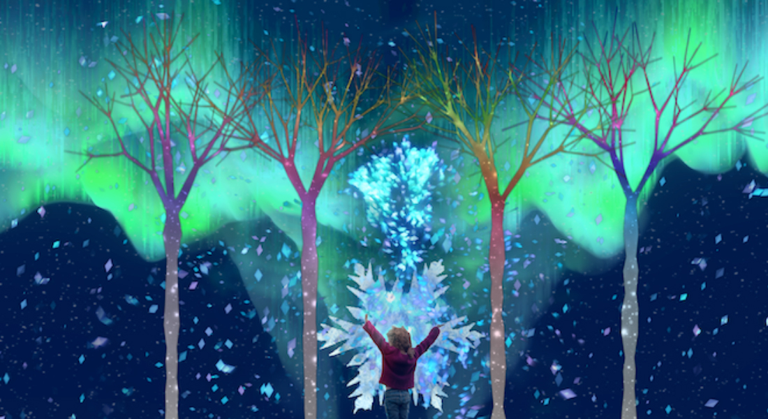 A small child interacts with a projected, multi-colored image of trees and the Northern Lights on a two-story wall.
