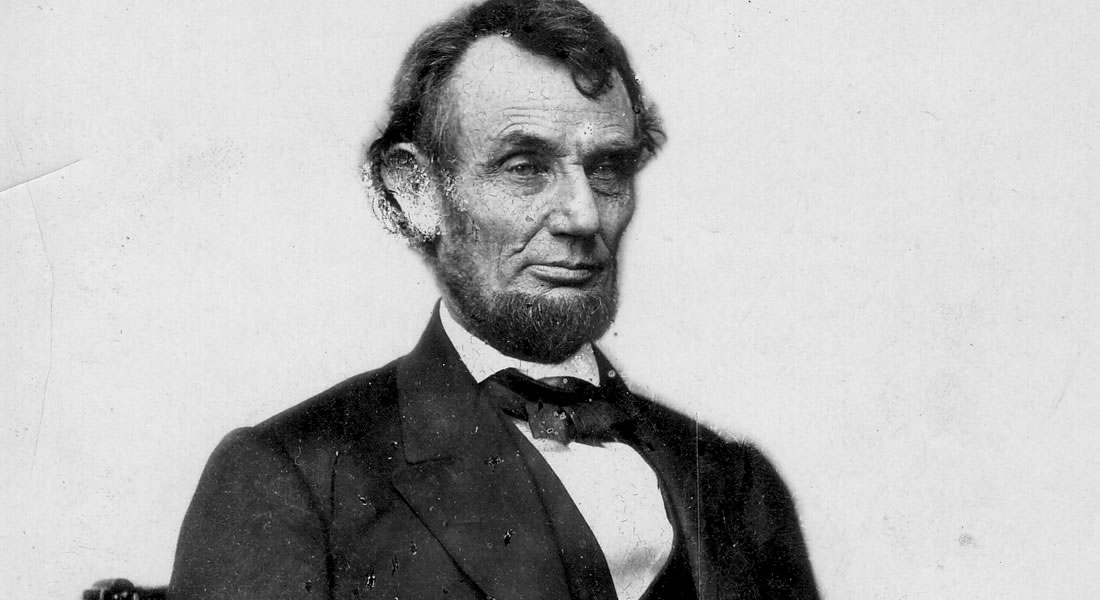 Abraham Lincoln seated, wearing his signature beard and a bow tie, looks slightly off-camera. He is photographed from the chest up. Link to learn more.