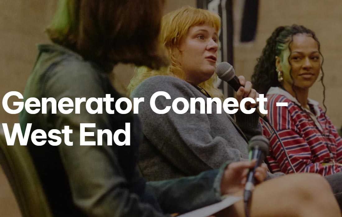 Three young women are sat down in a line. The middle woman is holding a microphone and looking out into an audience. She has ginger hair and the other two have dark brown hair