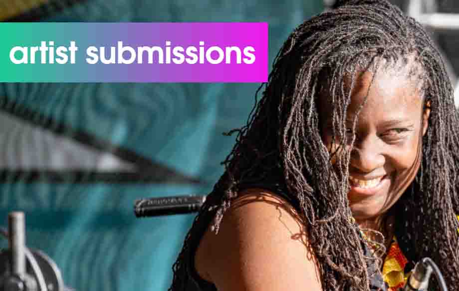 A woman is positioned to the right of the image, smiling and looking out past the camera. She has long brown hair. The wording 'artist submissions' is also visible to the left of the image, written in white.