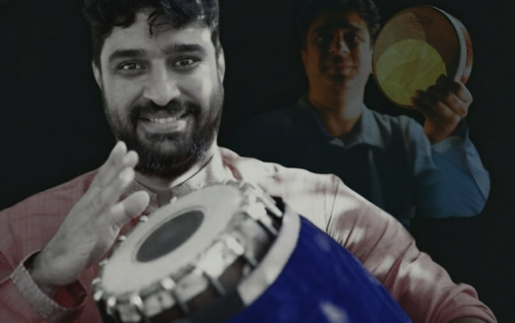 A young man with curly black hair is smiling at the camera and hitting a drum