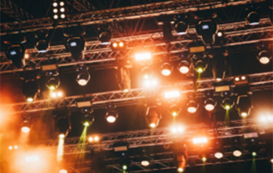 A lighting rig is seen with four rows of warm coloured lights hanging down