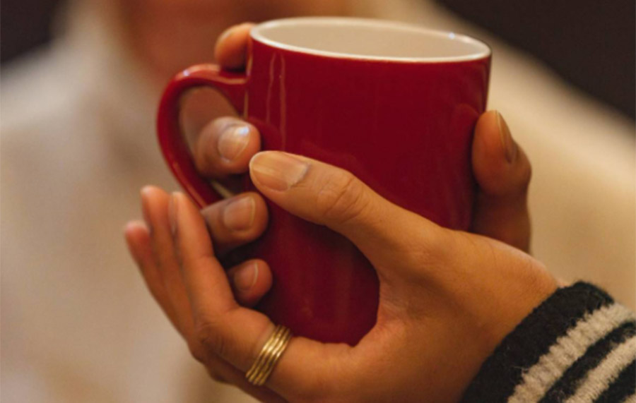A hand holding a red mug of tea