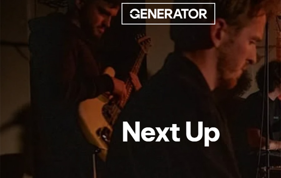 A young man with blonde hair and a beard is seen sat down, looking down. Behind him, another young man is wearing a long sleeved top playing bass guitar. The wording Next Up is written in white in the centre, and Generator's logo is at the top