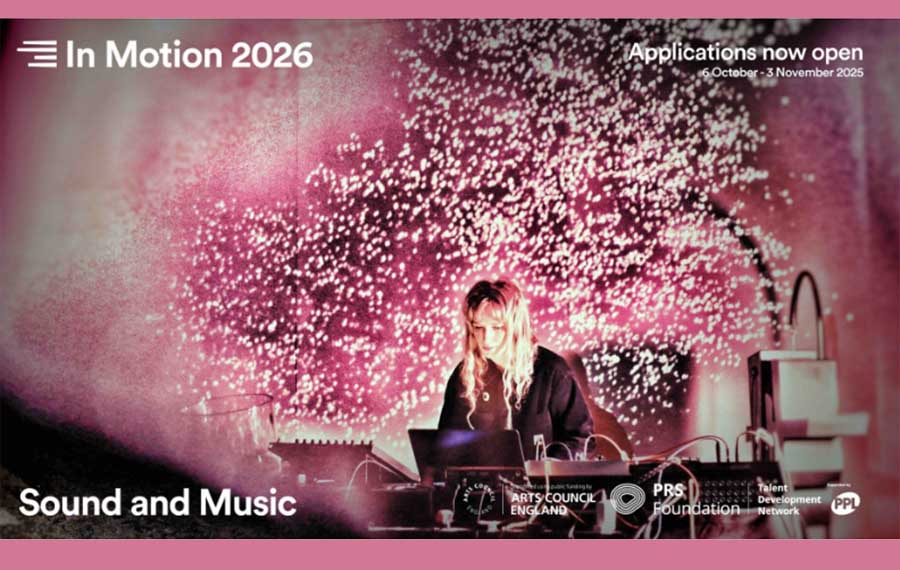 A young girl with long blonde hair is seen sitting down at her laptop with recording equipment surrounding her to the left and right. Pink confetti is going off behind her