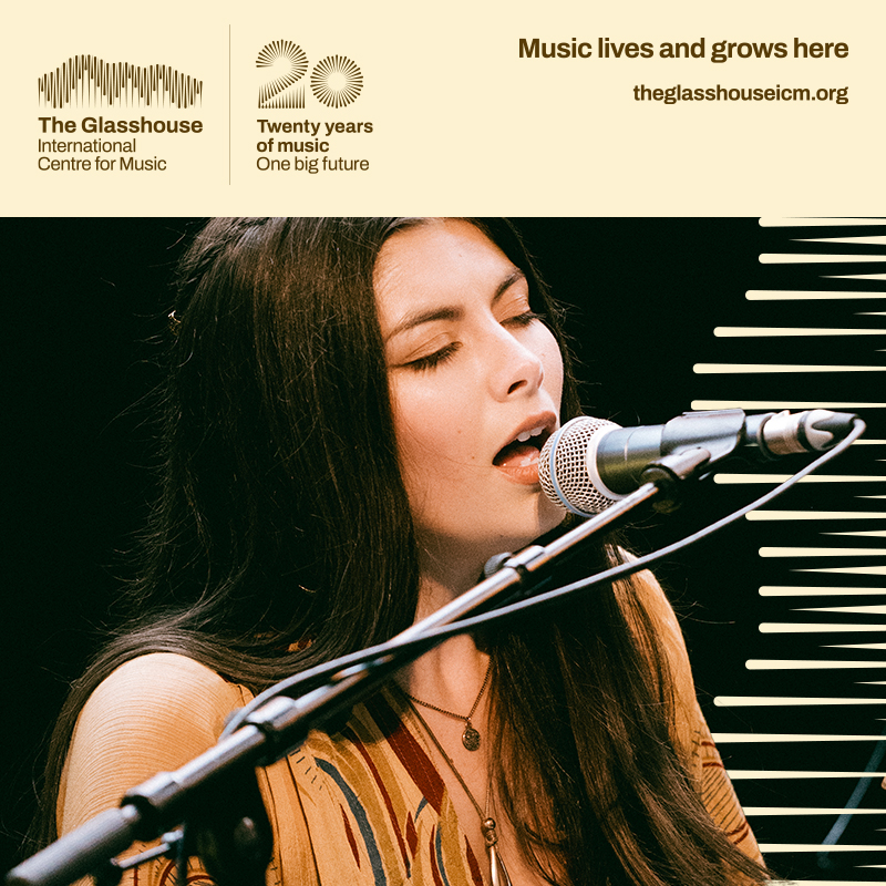 Elizabeth Liddle: A young woman with long dark brown hair is singing into a microphone with her eyes closed.