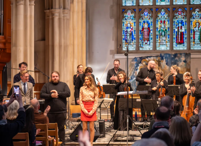 Orchestra and performers standing for an ovation in a church