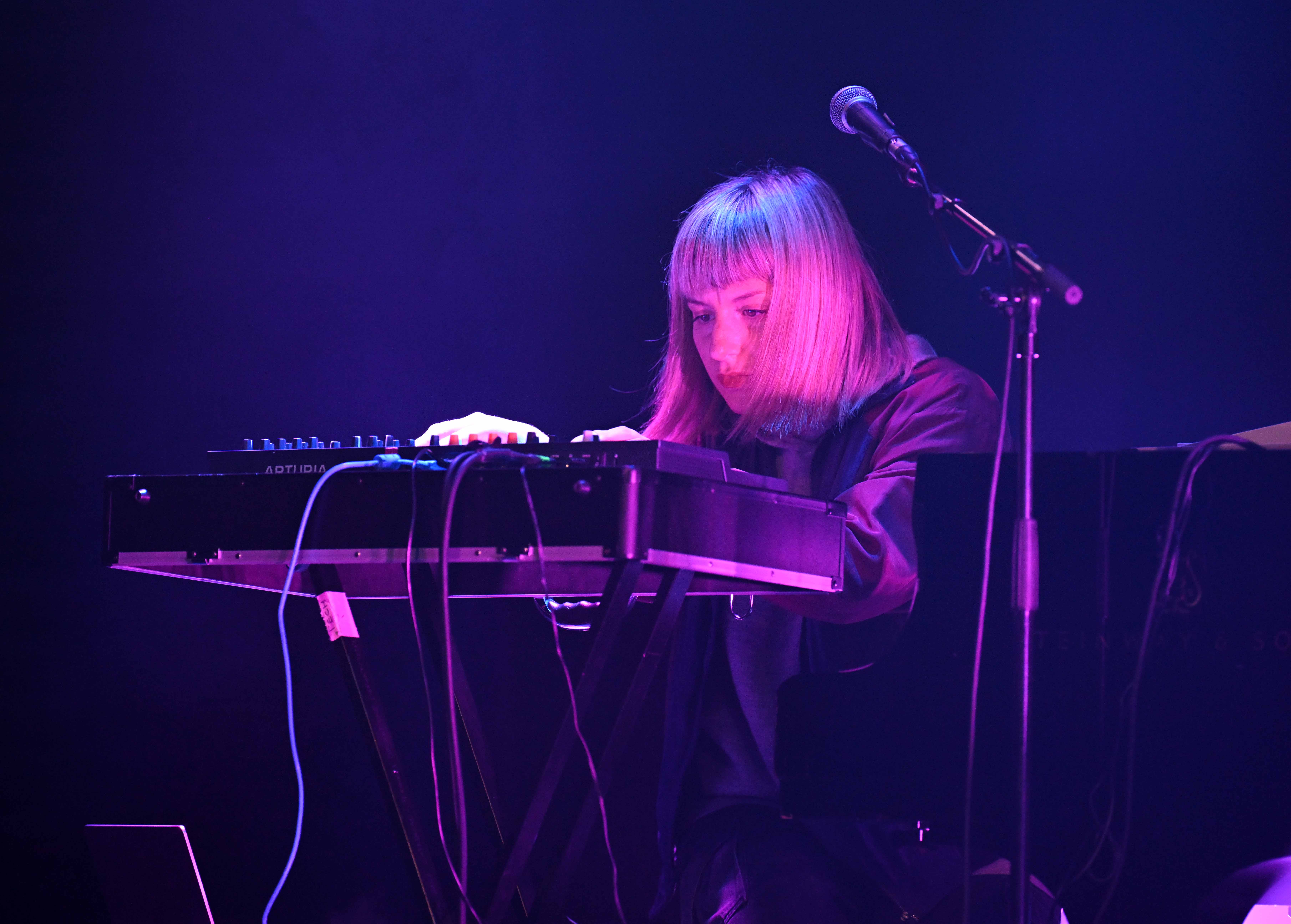 Maria from Mooonfish playing a synth behind the baby grand piano 