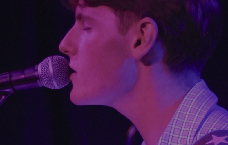 A young man is seen singing into a microphone