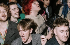 A group of people are in a crowd, all looking the same direction towards a performance