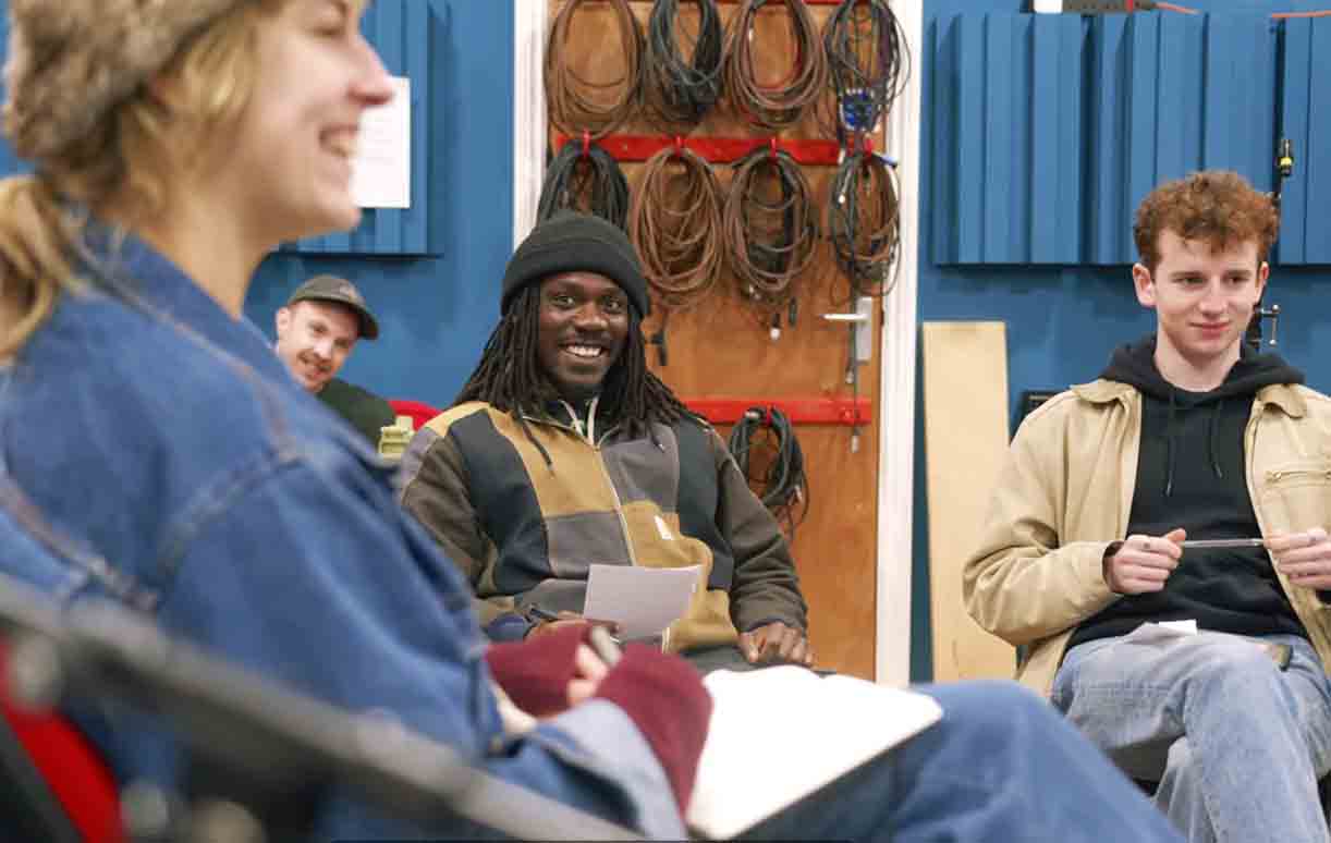 A group of people are smiling at each other and sat down on chairs