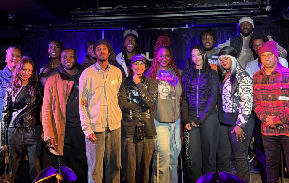 A group of people are stood in front of a stage smiling at the camera