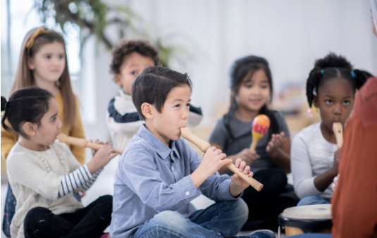 A group of children are sat playing recorders