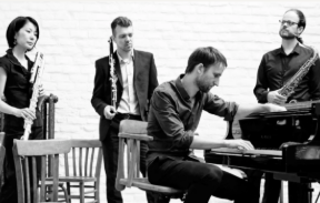 Four musicians are playing musical instruments: one sat at a piano, the rest playing woodwind instruments