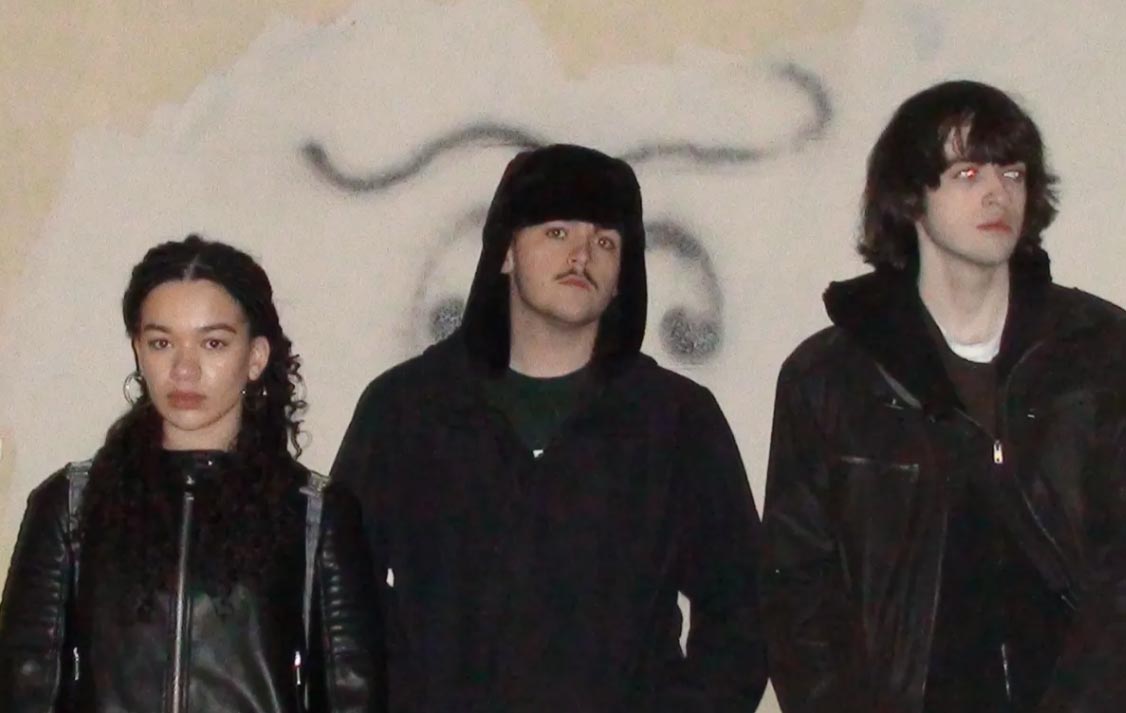 Three people are stood in a line staring directly into the camera