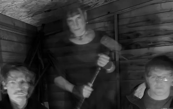 Three individuals are sat down staring straight into the camera. The image is blurry