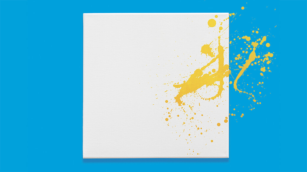 A blank, white canvas hangs unframed on a light blue wall. Bright yellow paint is splattered across the right side of the canvas and onto the wall.