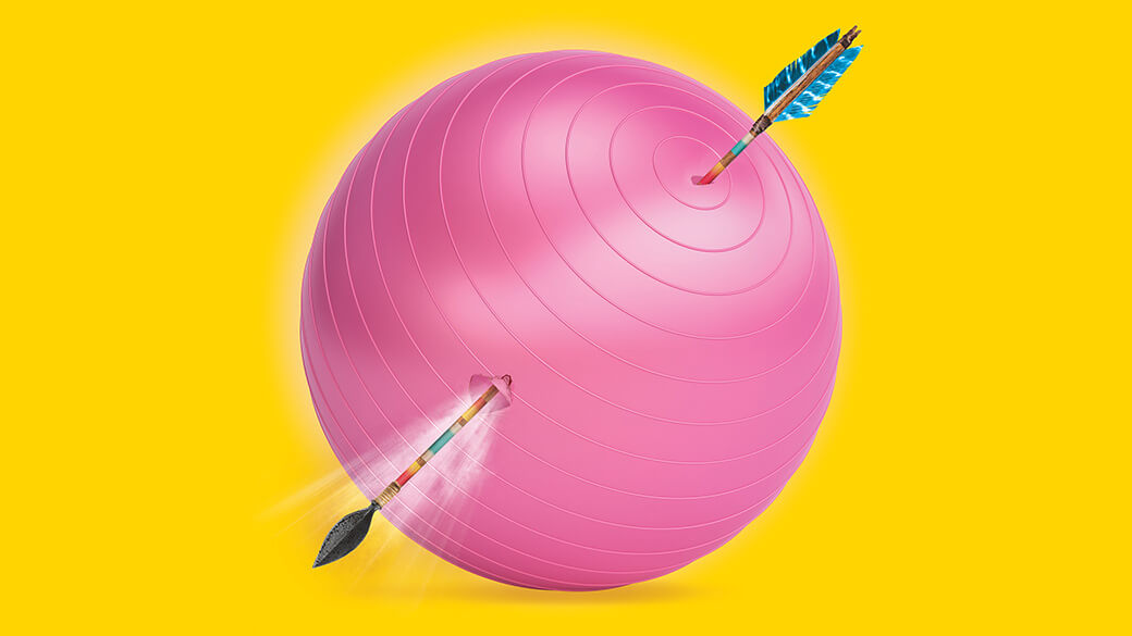 A colorful, traditional Native arrow with turquoise feathers pierces through the top and side of a large, pink exercise ball. Air seeps out of the arrow’s exit point, implying that the exercise ball is about to deflate.