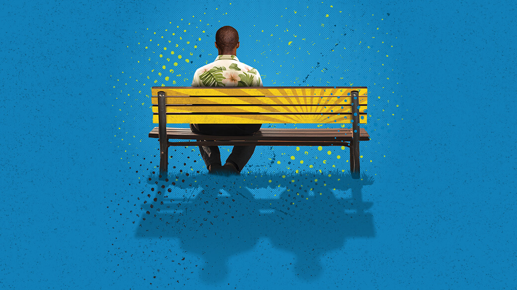 A man wearing a Hawaiian shirt sitting on a yellow bench with his back to us on a blue background
