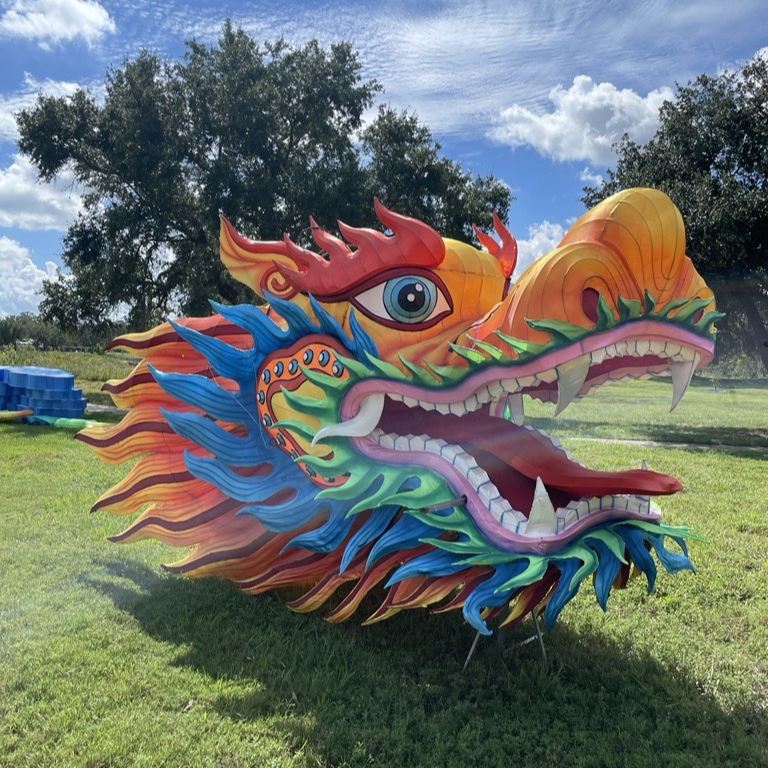 Chinese dragon head lantern rests on the grass in the sunshine. 