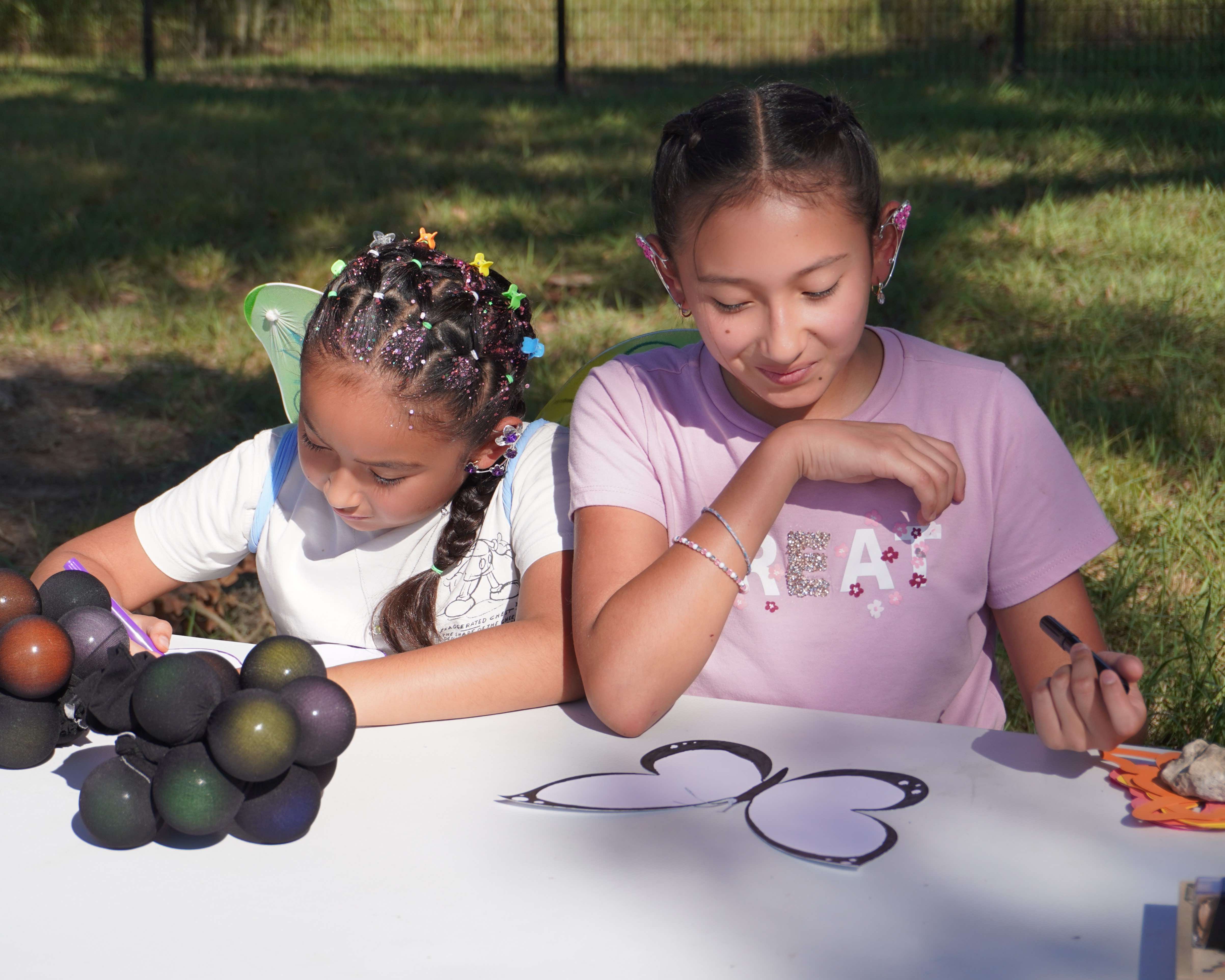 Two young girls make nature themed crafts. 