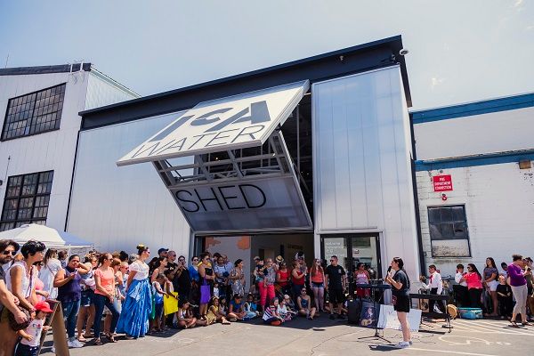 People dancing and celebrating in front of a large warehouse space.