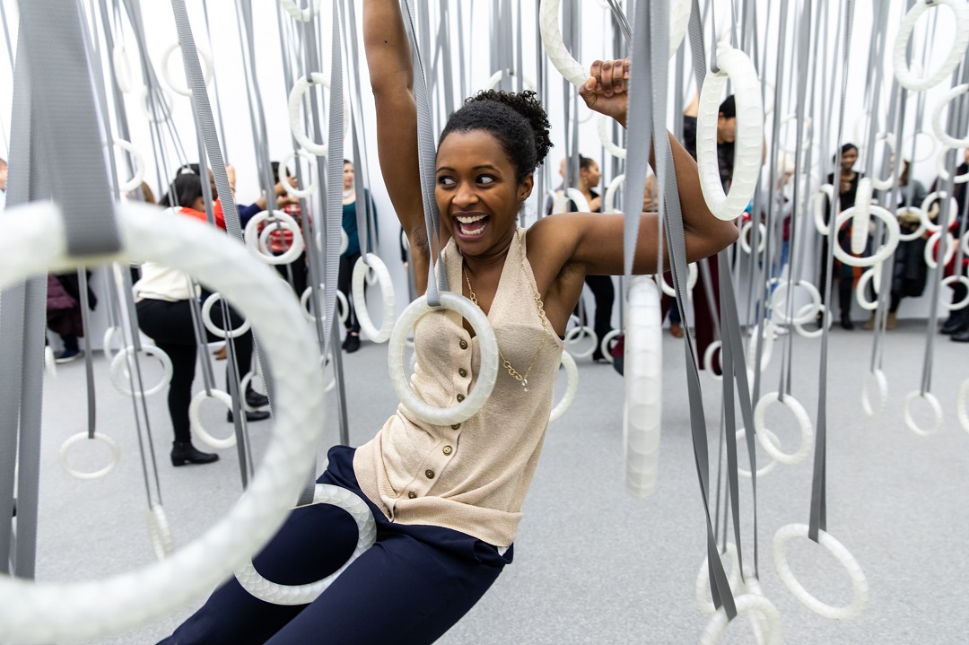 Person climbing through exercise rings.