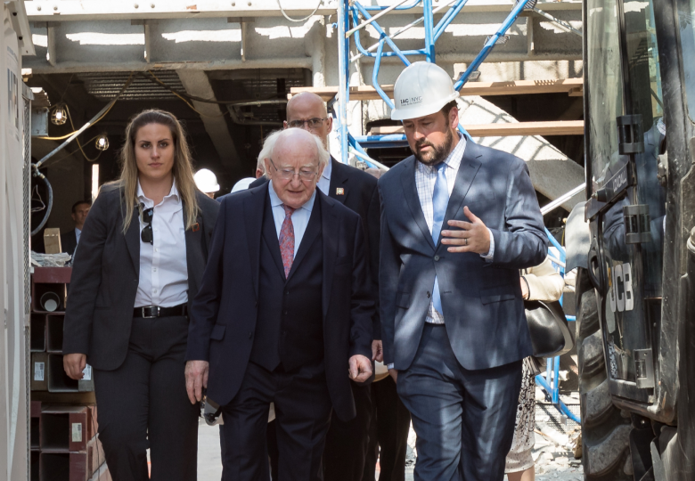 Aidan Connolly and former President of Ireland Michael D. Higgins tour a construction site with security personnel.