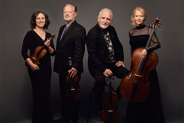 The four players of the Brodsky Quartet in smart black concert dress with their stringed instruments.