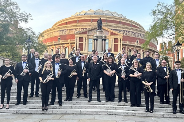 Members of the Carlton Main Frickley Colliery Band in black concert dress stood on the steps outside the Royal Albert Hall with their instruments.