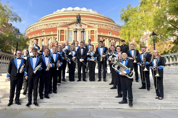 Members of the Hepworth Band in blue and black concert dress stood on the steps outside the Royal Albert Hall with their instruments.