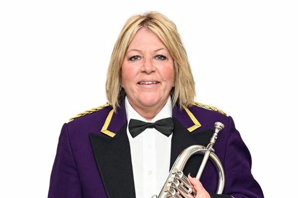 Flugel horn player Lucy Cutt in purple suit concert dress with her silver brass instrument.