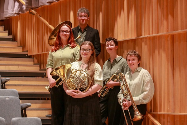 Five members of Bridge St Brass quintet in green concert dress with their instruments.