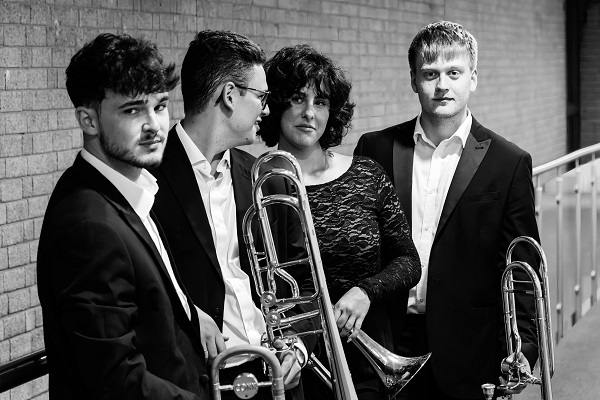 Four members of InSlide Out Trombone Quartet in black tie concert dress with their instruments.