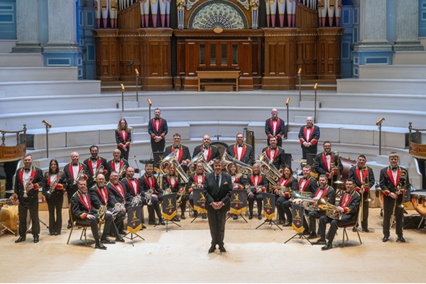 Members of the Black Dyke Band in concert dress sat in formation with their instruments in Huddersfield Town Hall.