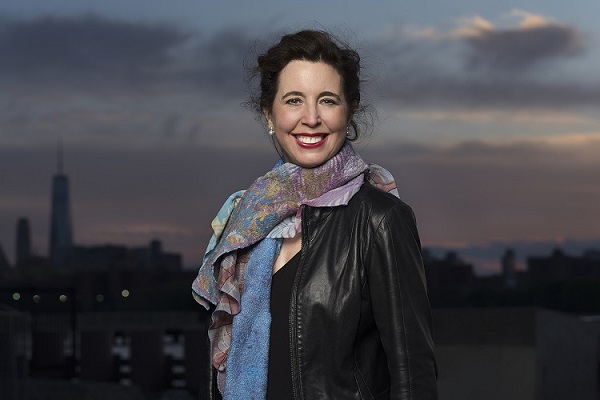 Pianist Angela Hewitt in casual dress with a city skyline in the background.