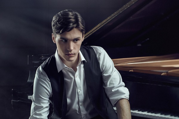 Pianist Jaeden Izik-Dzurko in concert dress at a piano